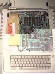 geöffneter Apple IIe. Links das Netzteil, welches keinen Lüfter benötigte. Der mit Klettverschlüssen versehene Deckel ist aufgeklappt.