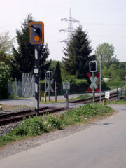 Unbeschrankter Bahnübergang in Deutschland mit Überwachungssignal (links), Straßensignal und Andreaskreuz